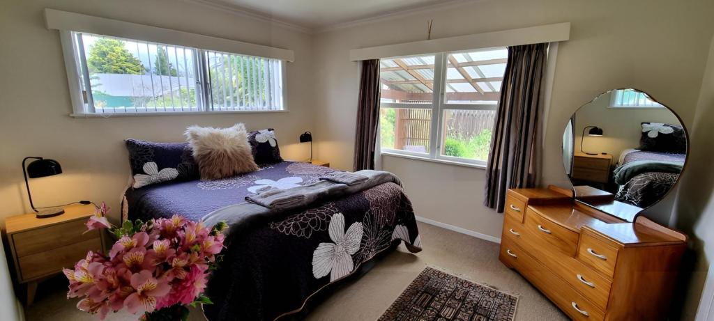 Un dormitorio con una cama y un espejo grande. en Quiet cul de sac, close to Abel Tasman, en Motueka