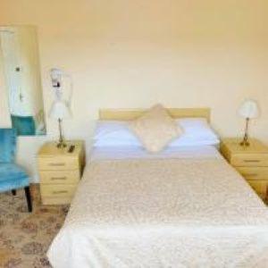 una camera con un letto bianco e due comodini di Redclyffe Lodge a Cork