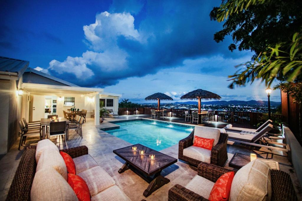 un patio con tavolo, sedie e piscina. di Stunning 4 bedroom villa a Saint John's