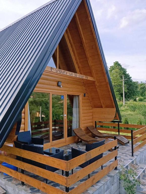 a cabin with a large roof with chairs on the porch at Brvnara Kao na dlanu in Rudnik