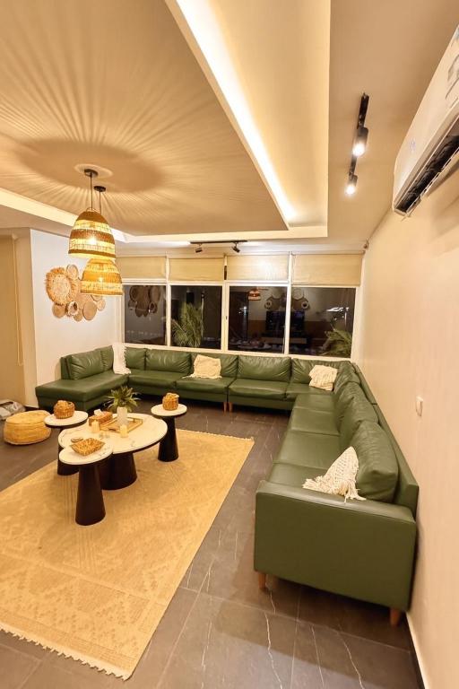 a living room with a green couch and tables at درة العروس - فن بيتش in Durat Alarous