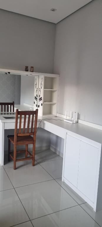 een witte keuken met een houten stoel en een bureau bij Casa da Vivi in Socorro