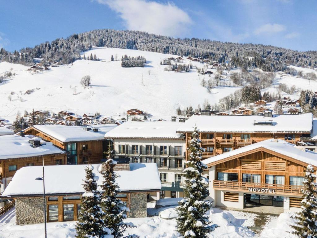 a resort in the snow with a mountain in the background at Novotel Megève Mont-Blanc in Megève