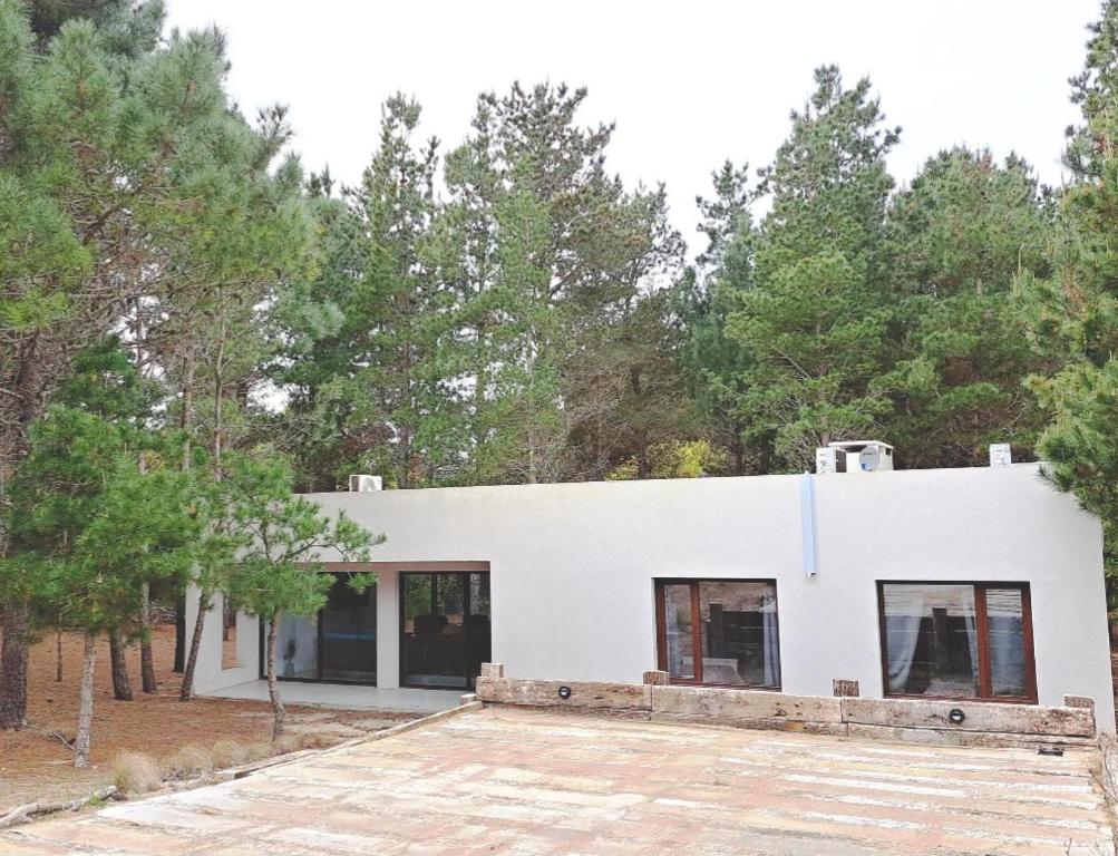 una casa bianca con alberi sullo sfondo di ecuestre53 a Pinamar