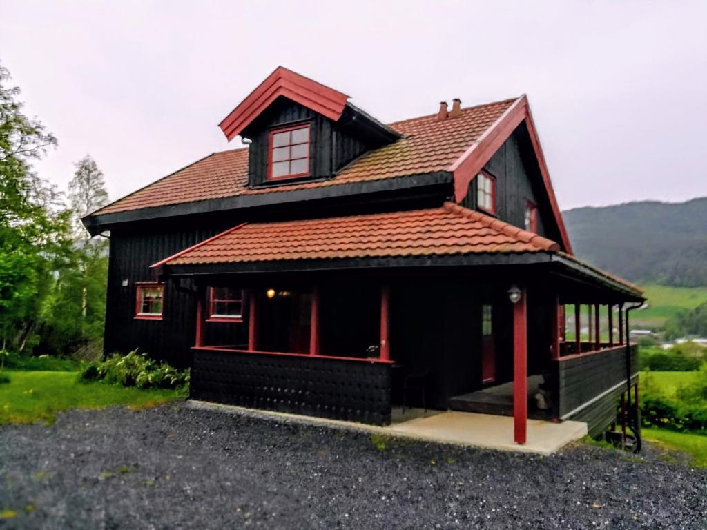 een klein zwart huis met een rood dak bij Skap Opplevelser! in Svingvoll