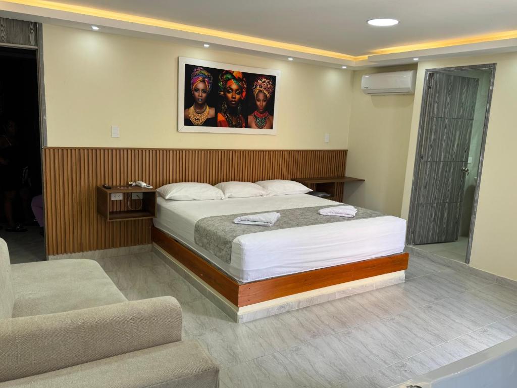 ein Schlafzimmer mit einem Bett mit einem Bild an der Wand in der Unterkunft Hotel Magistral Suiter in Quibdó