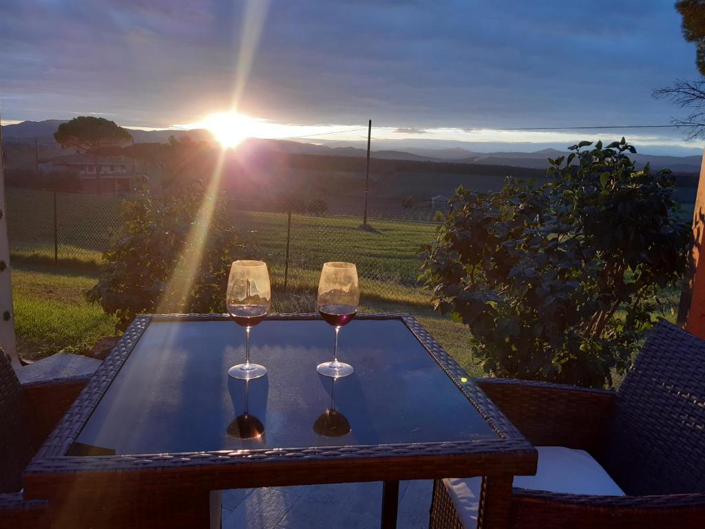 two glasses of wine on a table with the sunset at Il casale del Trebbio in Pila