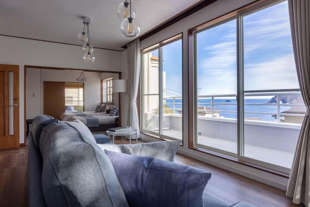 a living room with a couch and a view of the ocean at Ito Orange Beach Villa - Ocean View & Private Onsen in Ito