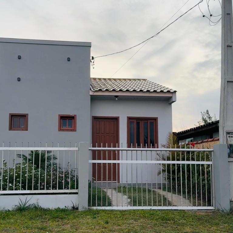 a white house with a white fence at kitnet 1 quarto in Arroio do Silva