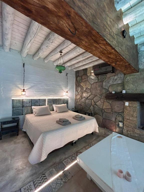 a bedroom with a large bed and a stone wall at Posada Via Vento - Chacras de Coria in Ciudad Lujan de Cuyo