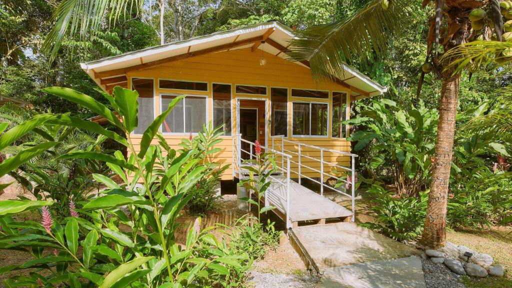 蓬塔乌巴Casa Amarilla in Playa Chiquita - with shared swimming pool -的森林中间的一个小黄房子