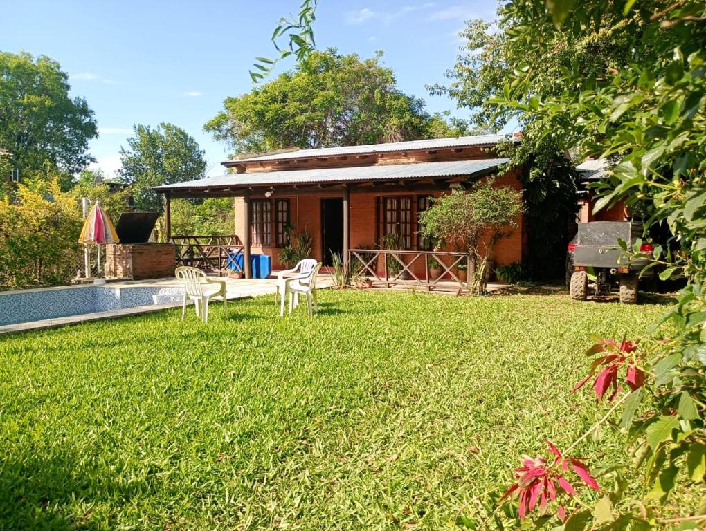 een huis met een tuin met stoelen en een zwembad bij Quinta La Nubia in Paso de la Patria