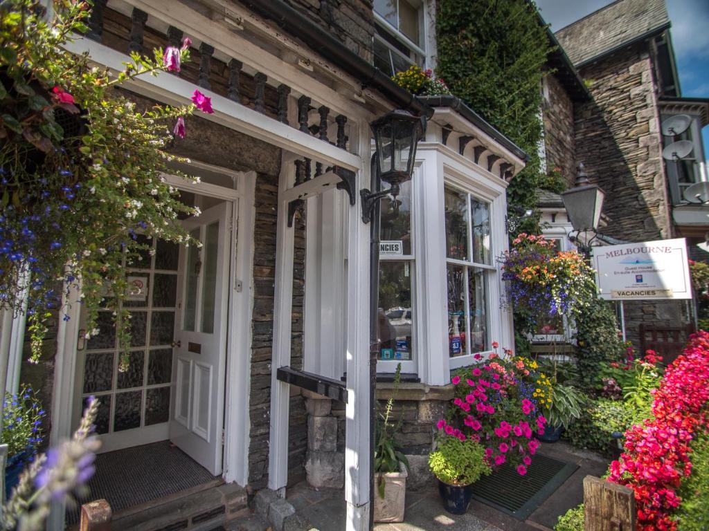 a house with flowers outside of it at Melbourne Guest House in Bowness-on-Windermere