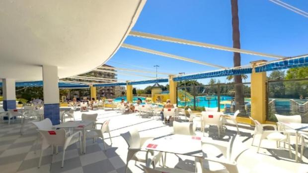 un patio con tavoli e sedie bianchi e una piscina di Minerva 518- Garden View a Benalmádena