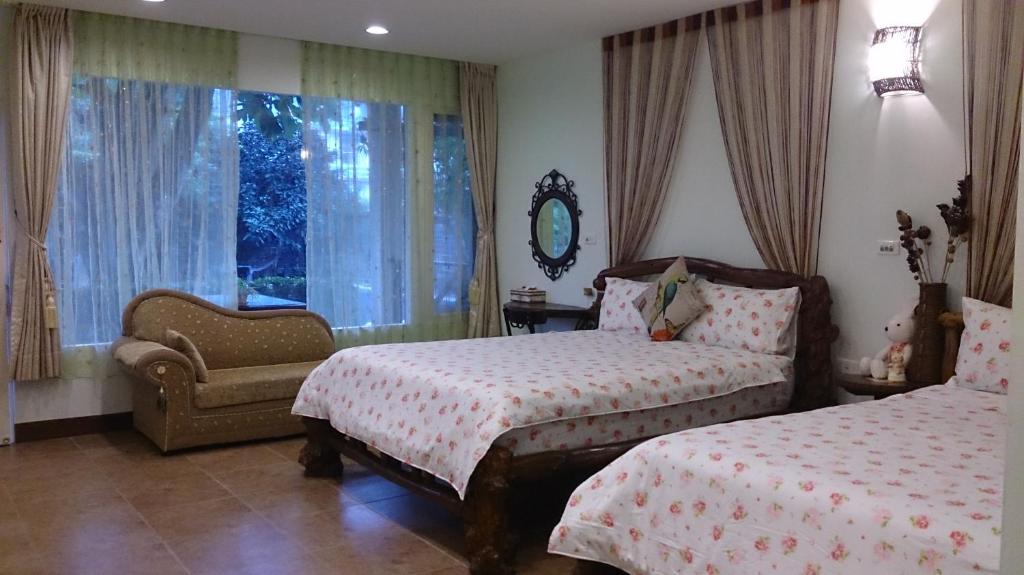 a bedroom with two beds and a chair and a window at Gengmengyuan B&amp;B in Xikou