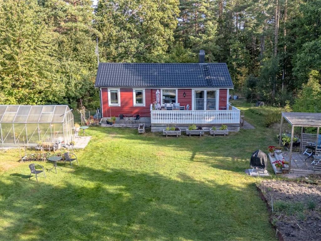 Köpmannebro5 person holiday home in KÖPMANNEBRO的院子里有一栋红色的房子，院子里还有一个温室。