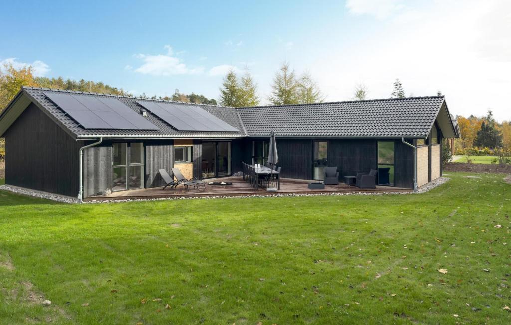 uma casa preta com um pátio e um quintal em Lovely Home In Ebeltoft em Femmøller