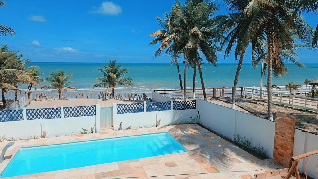 a swimming pool with the beach in the background at Casa da Janelas Azuis Praia Azul in Pitimbu