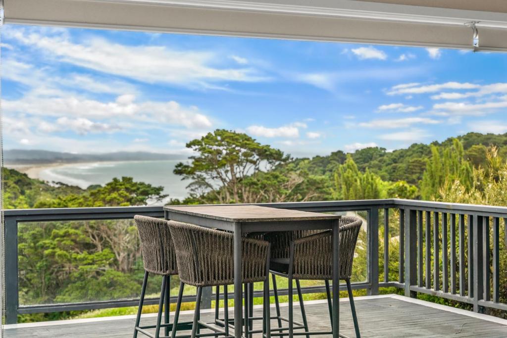 Waipu CoveTreetop Break - Waipu Cove Holiday Home的阳台上的桌子和椅子，可欣赏海景