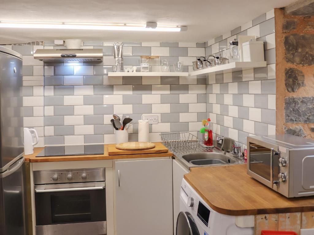 una cucina con un lavello e un piano di lavoro di The Snug a Y Felinheli