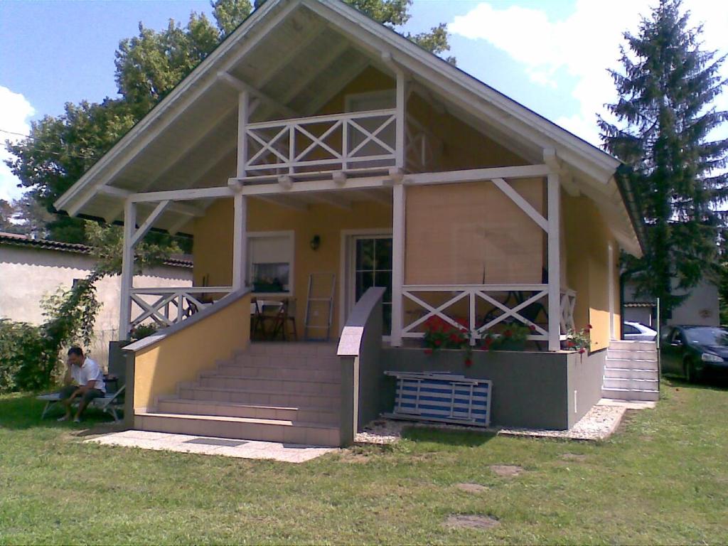 a small yellow house with a porch and stairs at Rozmaring Ház in Balatonlelle