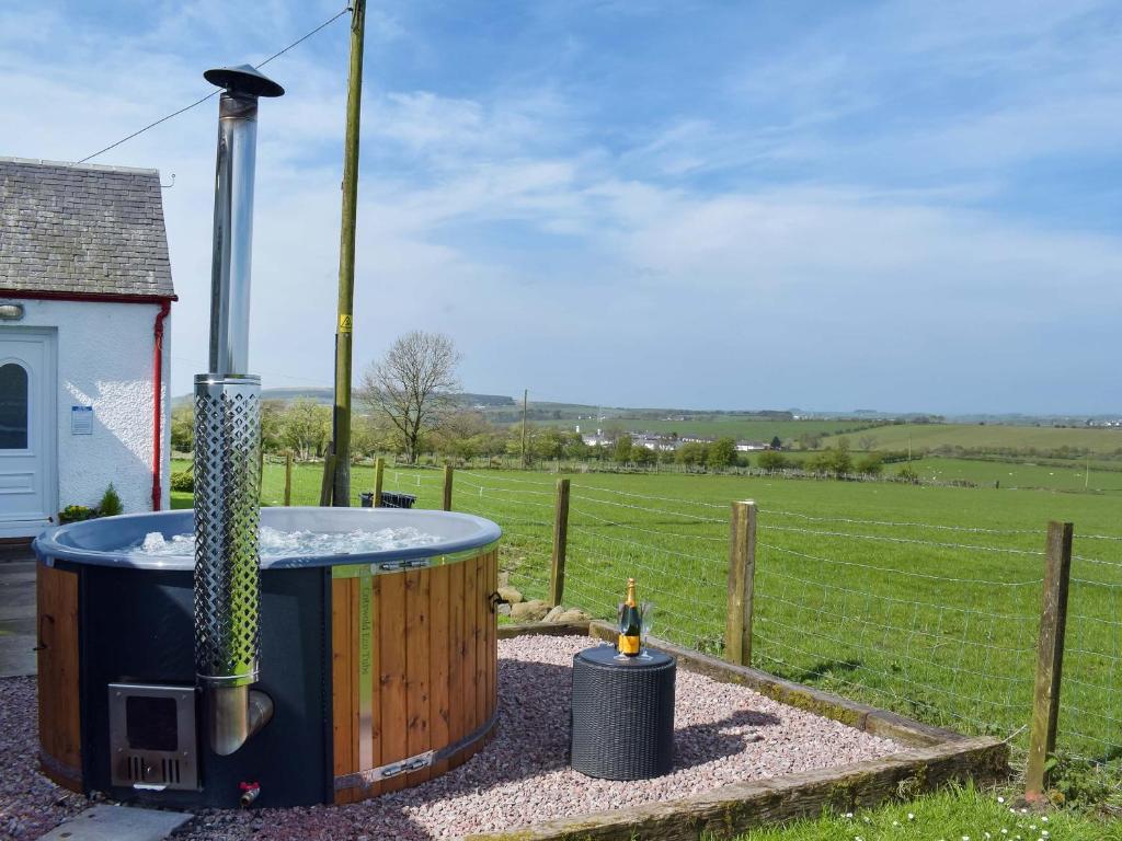 a hot tub in a yard next to a fence at Muirston Farmhouse - Uk44977 in Ochiltree
