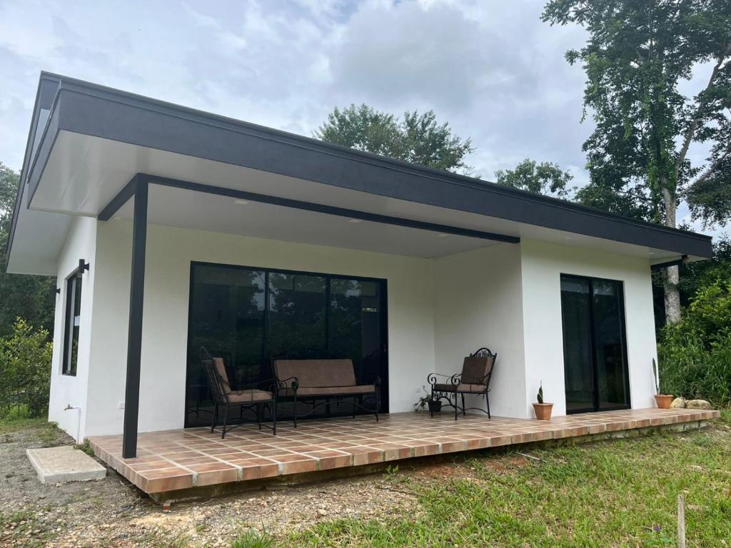 a small white house with a deck with two chairs at La casita in General Viejo