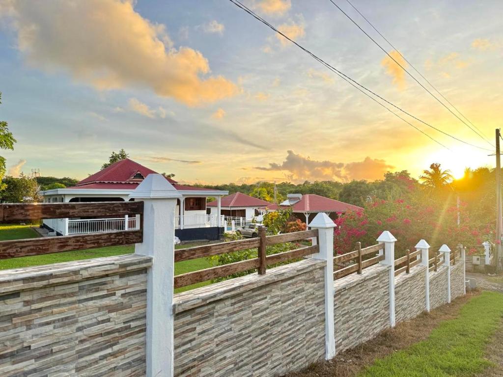 a white fence in front of a house at Gîtes du Domaine de la Canne à Sucre in Anse-Bertrand