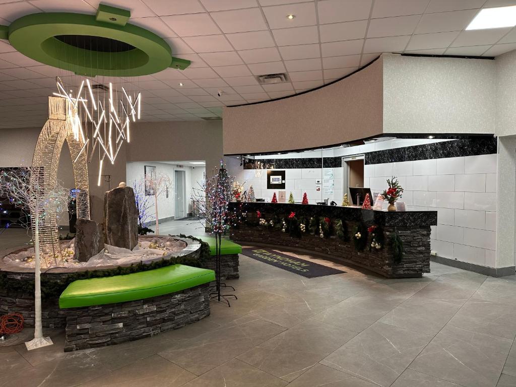 梅迪辛哈特Wyndham Garden Medicine Hat Conference Center的大堂设有酒吧，酒吧里有绿色座椅和树木。