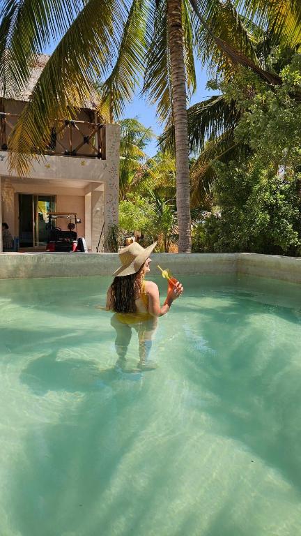 a woman wearing a hat in a swimming pool at Apartment with jacuzzi and beach club access in Telchac Puerto