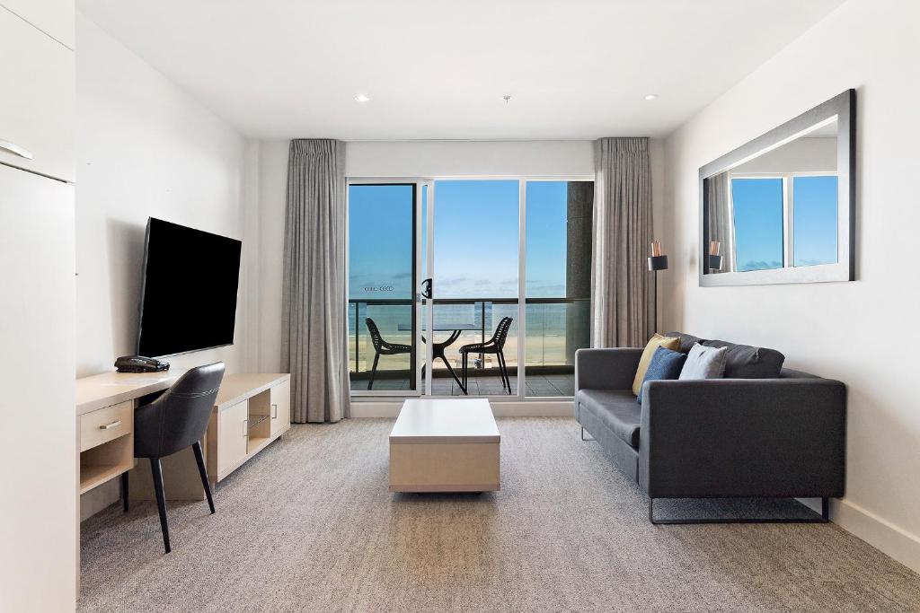 a living room with a couch and a television at Belle Escapes - Waves at The Bay in Glenelg