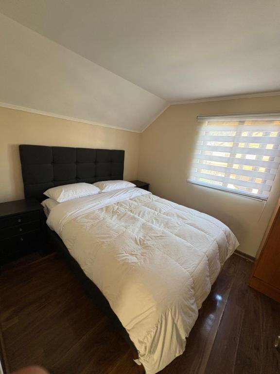 a bedroom with a large white bed with a window at Alojamiento casa in Temuco