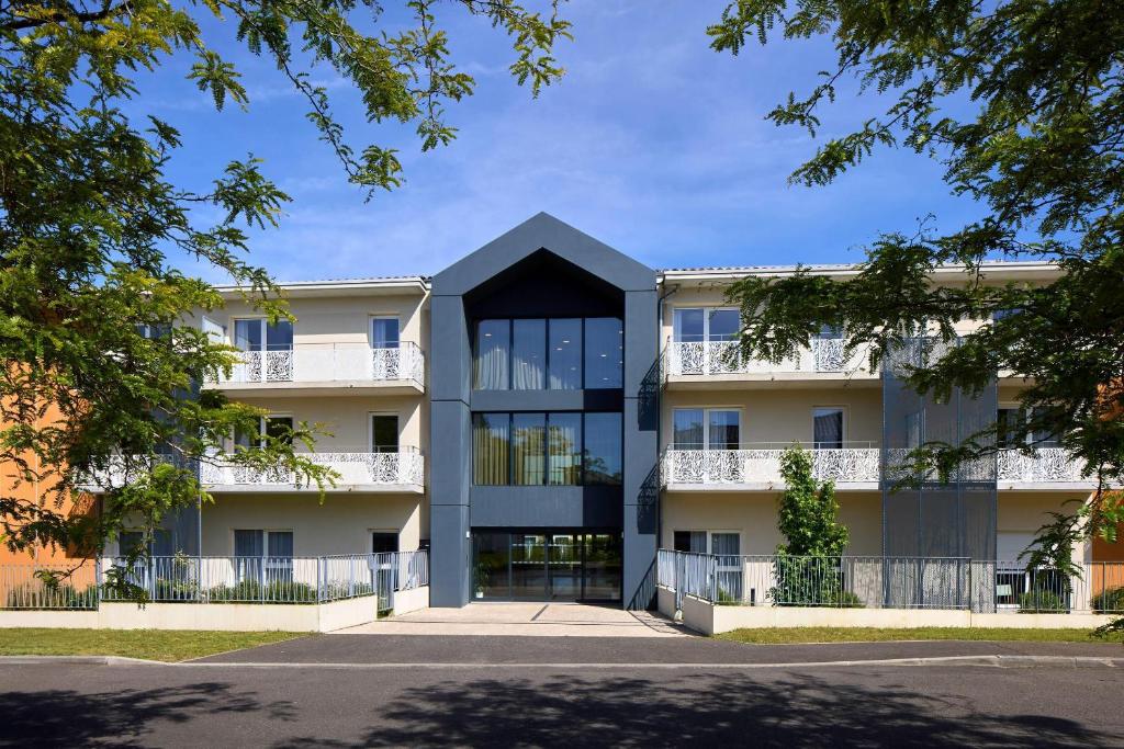 an apartment building with a black roof at Quality Suites Saint-Paul-l s-Dax in Saint-Paul-lès-Dax