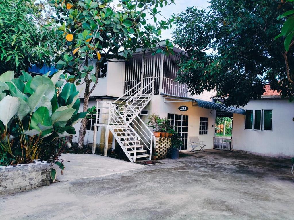 a white house with a staircase in front of it at Princess Iris Homestay in Penampang
