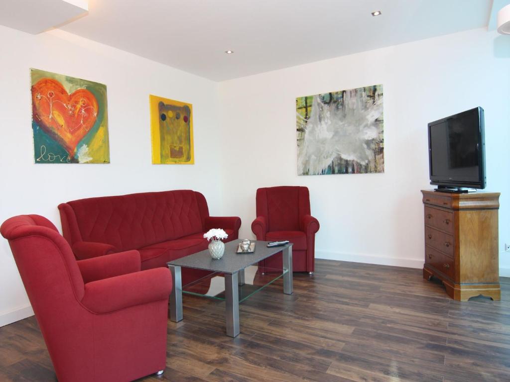 a living room with two red chairs and a tv at Chalet mit Außensauna in Wendorf in Wendorf
