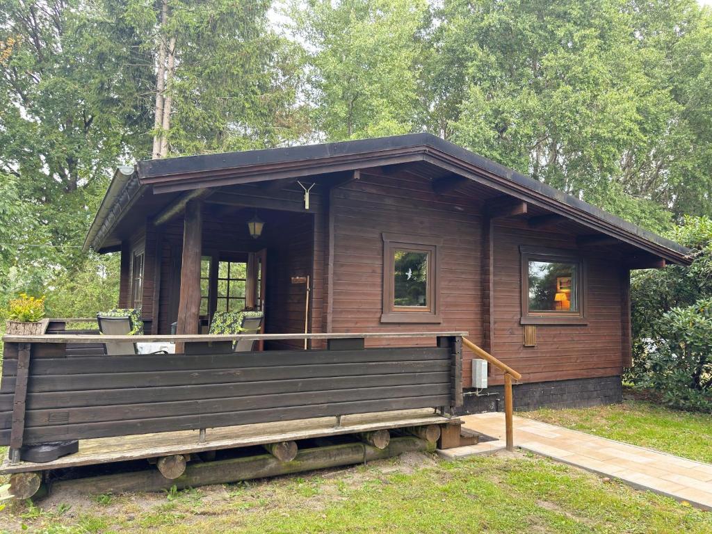 a small wooden cabin with a porch and a deck at Charmantes Ferienhaus mit Terrasse in der Südheide in Eschede