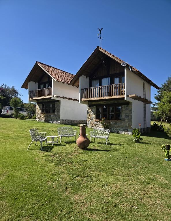 a building with benches in front of a yard at Cabañas Las orquídeas in Huasca de Ocampo