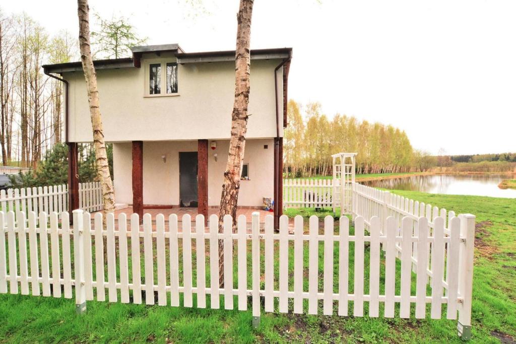 a white picket fence in front of a house at Holiday Home near Ko obrzeg with Private Pond in Nieżyn