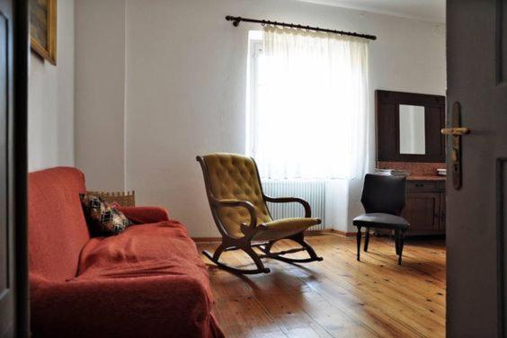 チヴィダーレ・デル・フリウーリにあるB&B Casa Carbonaraのリビングルーム(赤いソファ、椅子付)