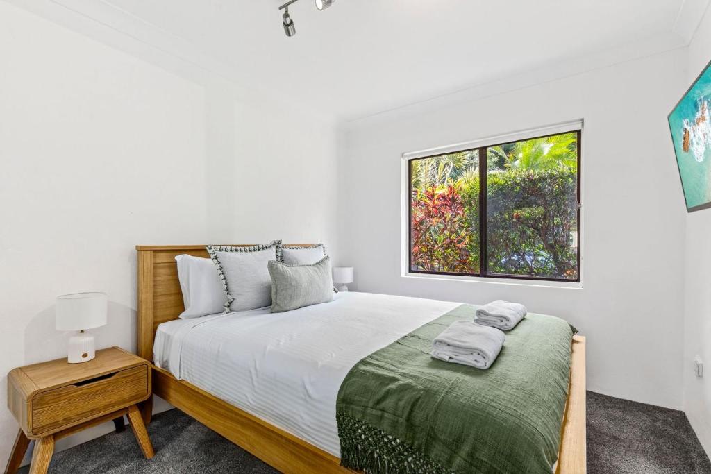 Surf's Up Sawtell في ساوتيل: غرفة نوم بيضاء مع سرير ونافذة