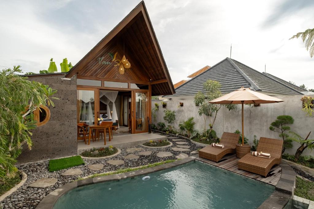 una casa con piscina con sedie e ombrellone di Van Sheva Ubud Villa ad Ubud