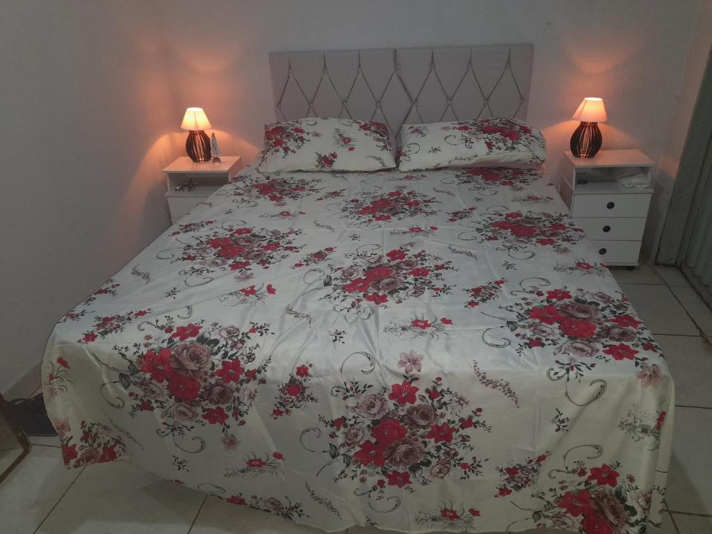 una camera da letto con un letto con fiori rossi di Cantinho Descanvida Temporada a Água Boa