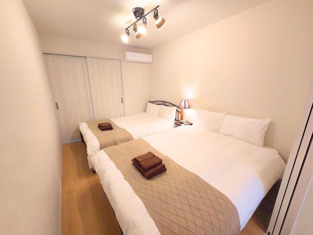 a bedroom with two beds with white sheets at 新大阪ゲストハウス 新大阪駅徒歩5分のリノベーション貸切宿 in Osaka