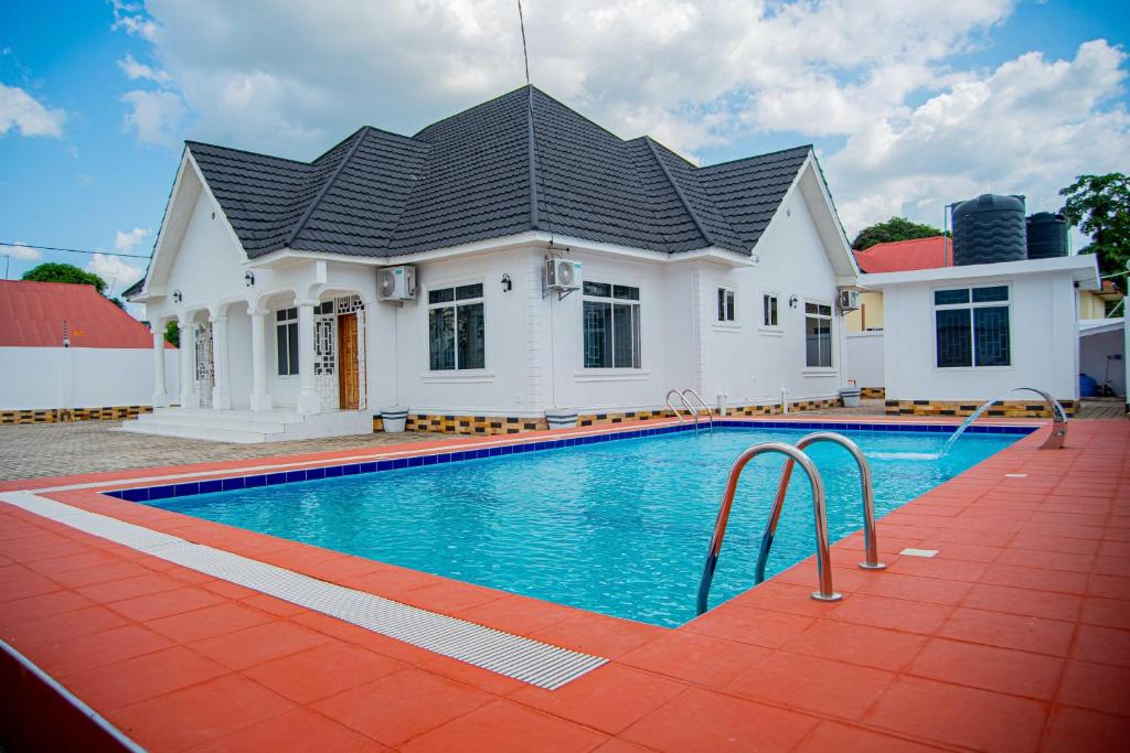 una casa con piscina di fronte a una casa di BNJ Royal Palace a Dar es Salaam