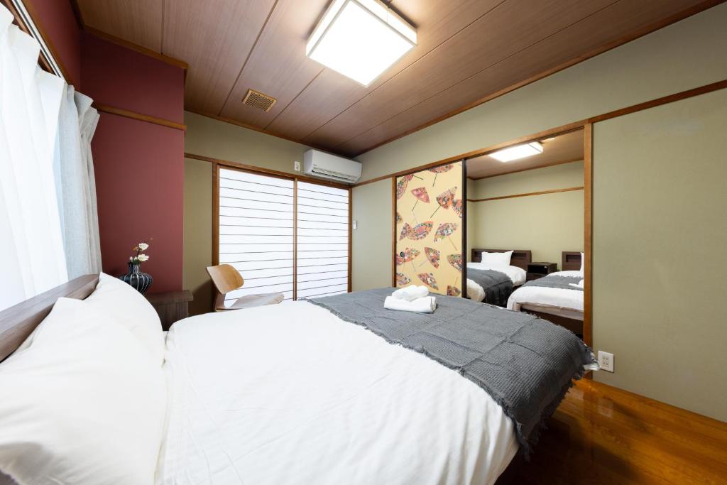 a bedroom with two beds and a mirror at HITOYADO kanazawa in Kanazawa