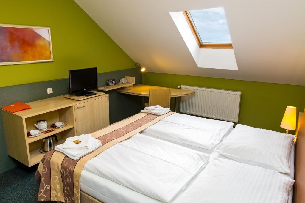 a bedroom with a bed and a desk with a computer at Hotel Rieger Garni in Jičín