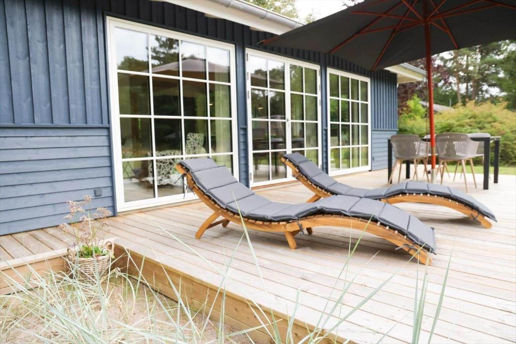 尼克宾西兰岛11126-1-Nykobing-Sj-Slaenhaekken-18的木制甲板设有2张长椅和遮阳伞