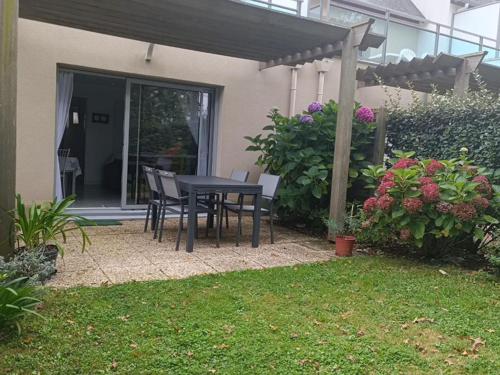 a patio with a table and chairs under a pergola at Appartement rez-de-jardin proche Port Crouesty, 4 pers, tennis, piscine, wifi - FR-1-775-50 in Arzon