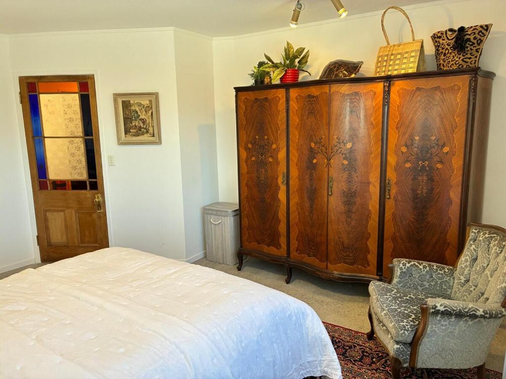DruryExecutive Short Term Rental Drury South Auckland的一间卧室配有大型木制橱柜和椅子