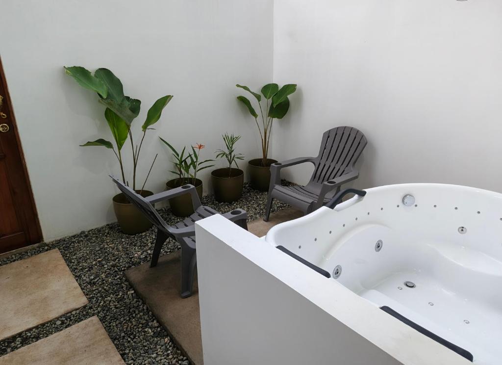 a bathroom with a tub and chairs and plants at The Cat And The Kraken Jacuzzi Suites in Siquijor